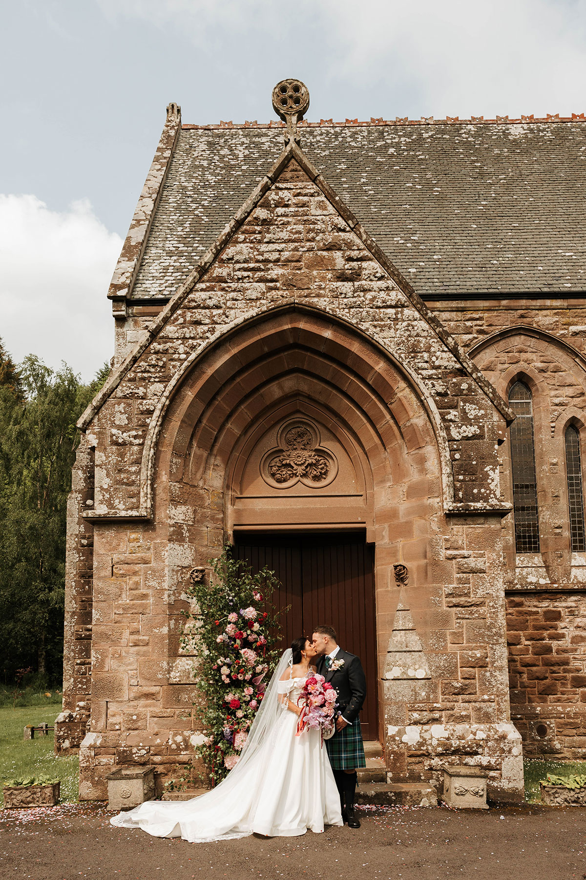 Bride and groom kissing outside St Palladius Church during Drumtochty Castle Aberdeenshire wedding