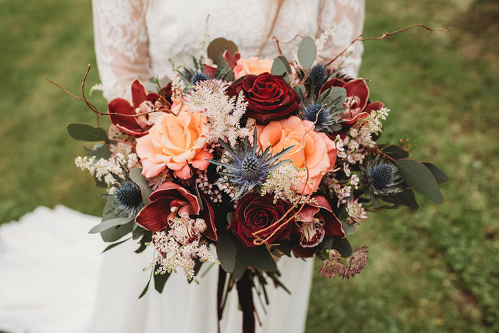 Brightly coloured bouquet featuring red roses and thistles