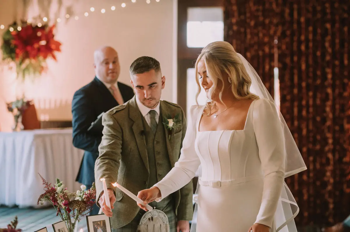 a bride and groom performing a candle-lighting during a wedding ceremony