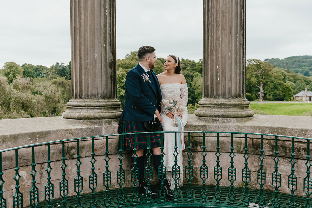 Bride and groom at the Burns Monument in Alloway, seated between stone columns overlooking the surrounding countryside.