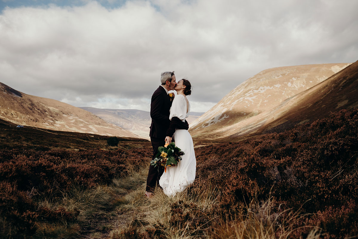 Mar Lodge Estate wedding, a bride and groom kissing amid the mountain scenery of the Cairngorms