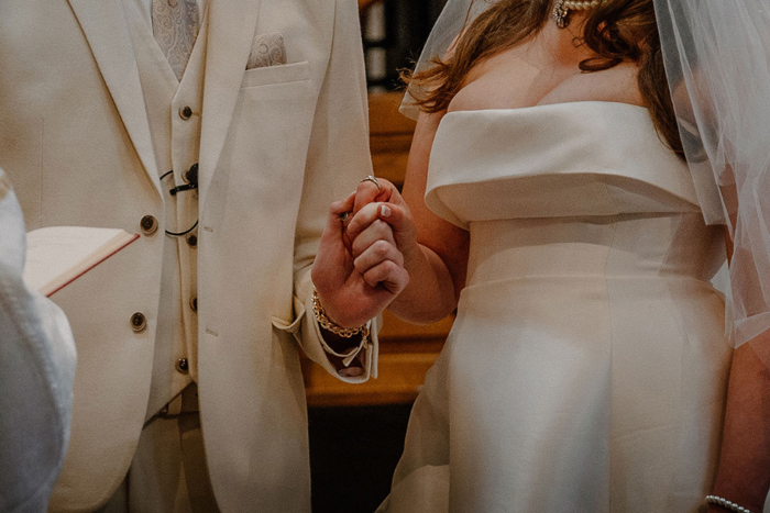 Close up of the bride and groom holding hands