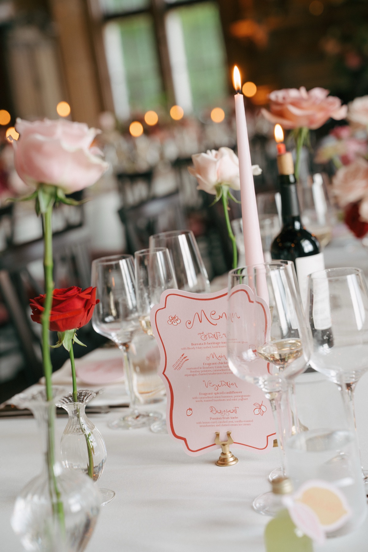 Close-up of wedding table styling at Barnbougle Castle, featuring personalised pink menus, blush roses, candles and elegant glassware.