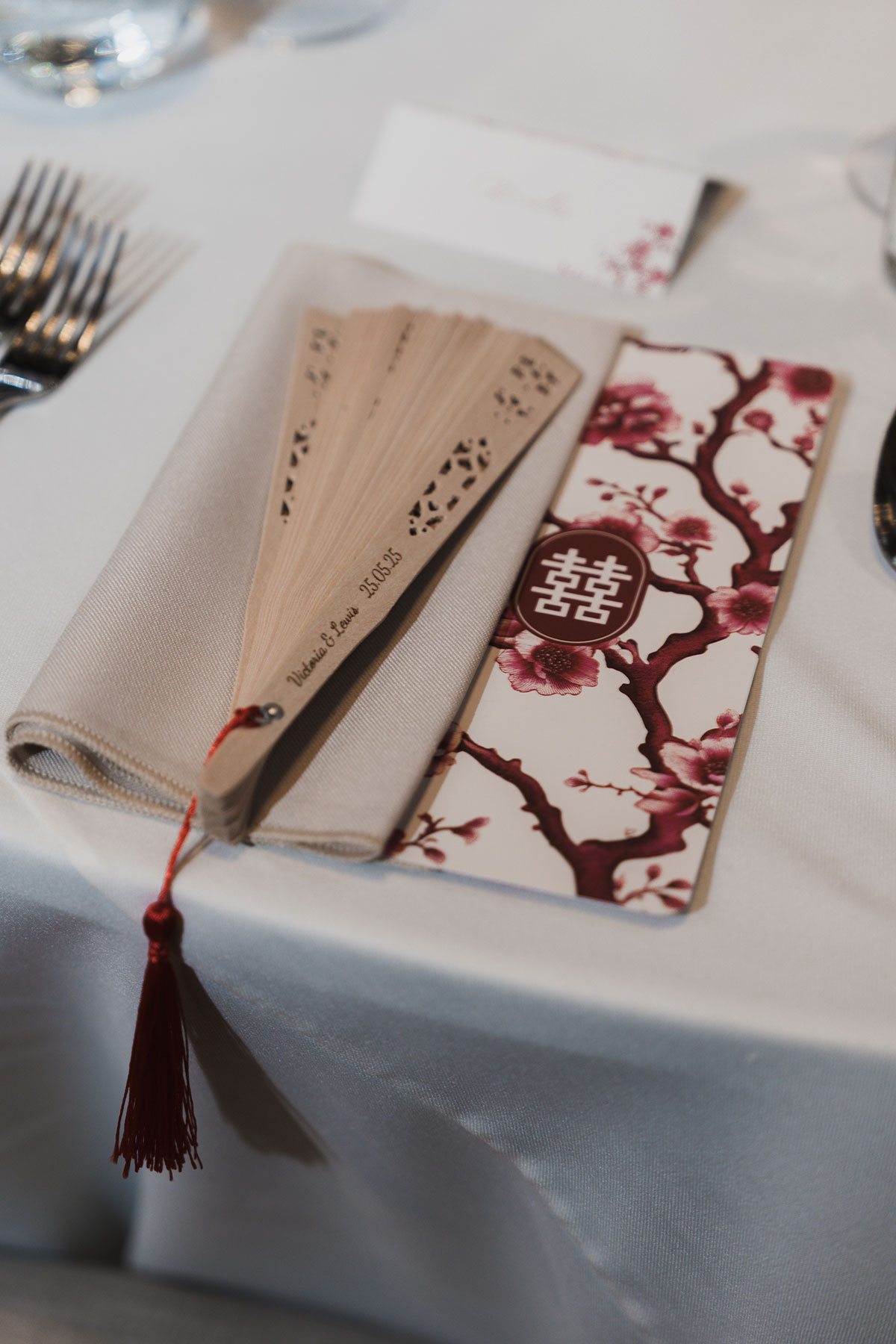 Chinese-inspired wedding fan and menu detail with traditional motifs on reception table