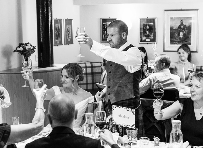 A black and white photo of people raising their glasses in a toast