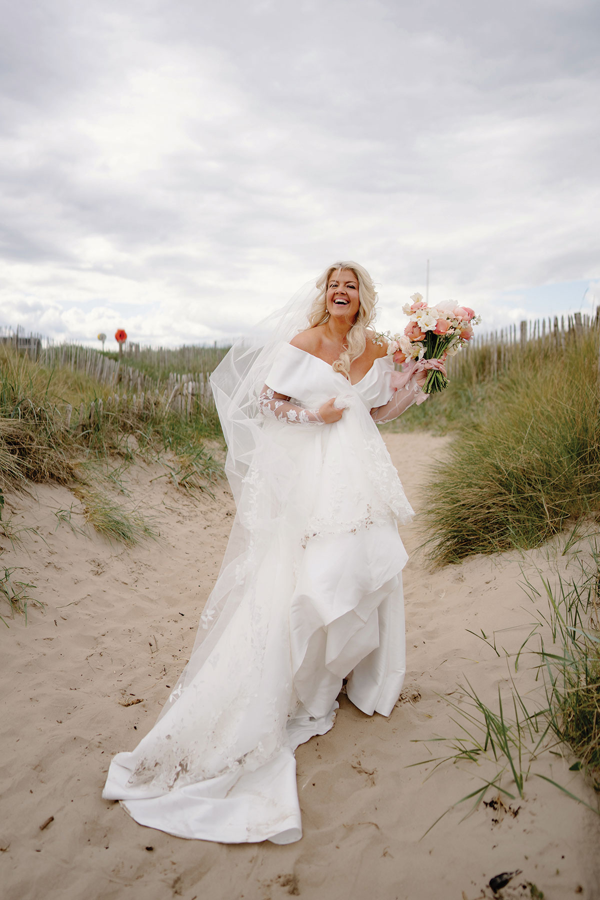 Bride carrying a pink and white bouquet among the sand dunes during an Old Course Hotel wedding in St Andrews