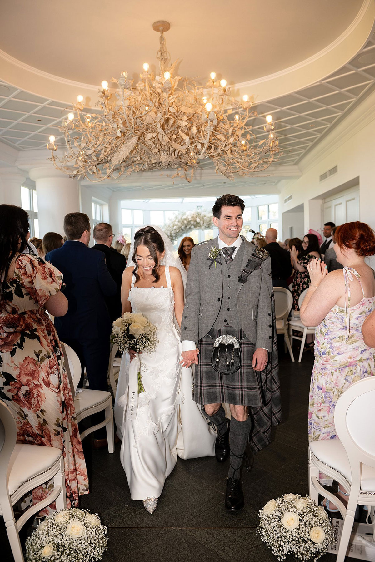 Newlyweds walking down the aisle after their ceremony at Old Course Hotel wedding in St Andrews with guests applauding.