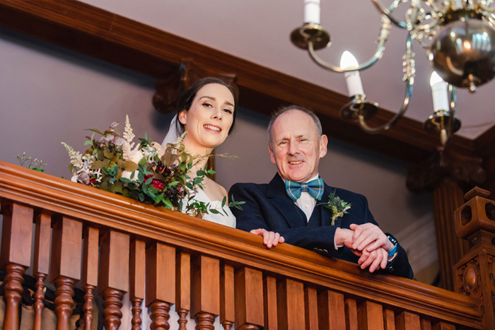Bride and her father looking over the balcony 