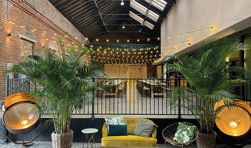 balcony at Engine Works with a yellow velvet couch and plants