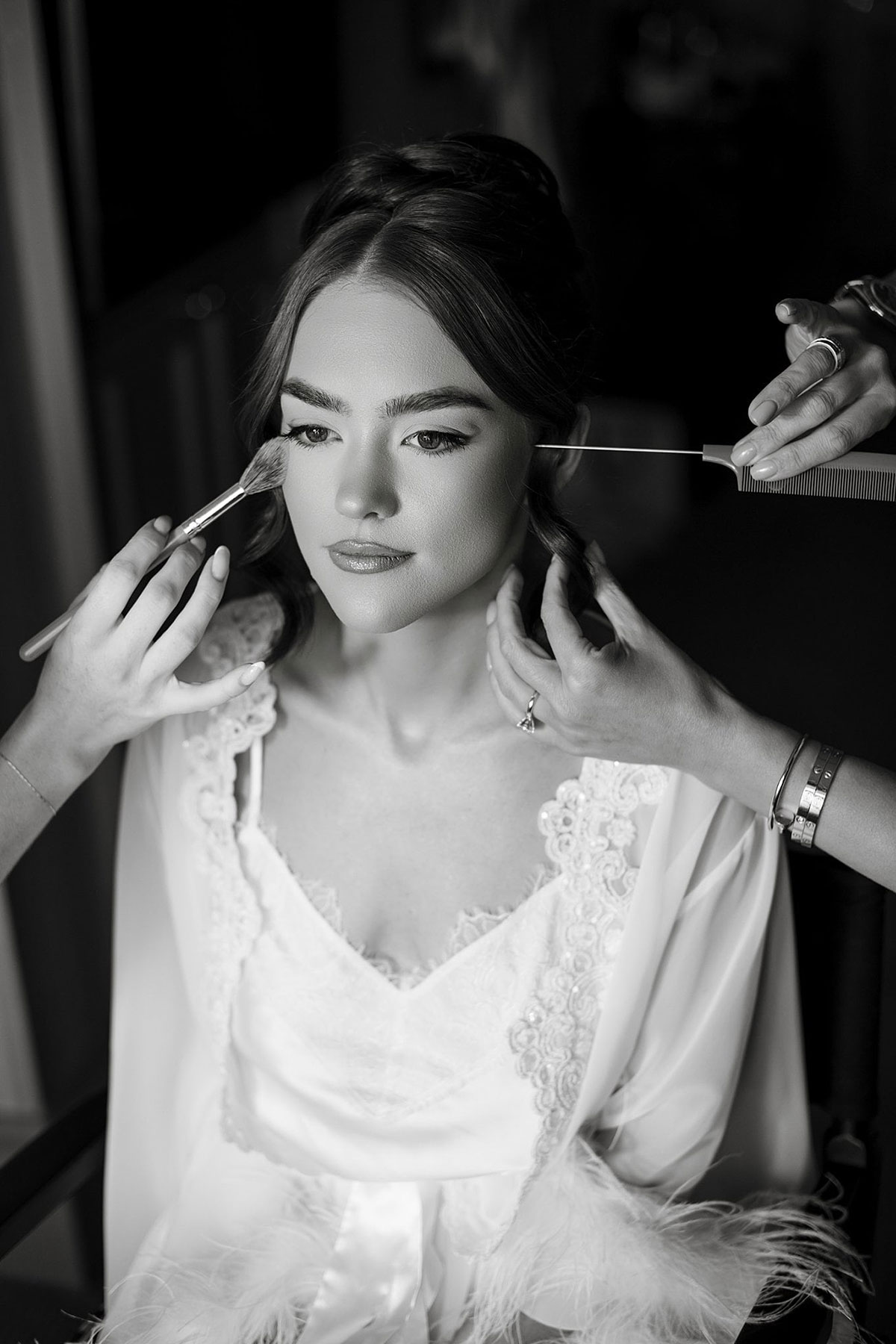 Black and white bridal portrait as hair and makeup artists prepare bride on wedding morning at Old Course Hotel.