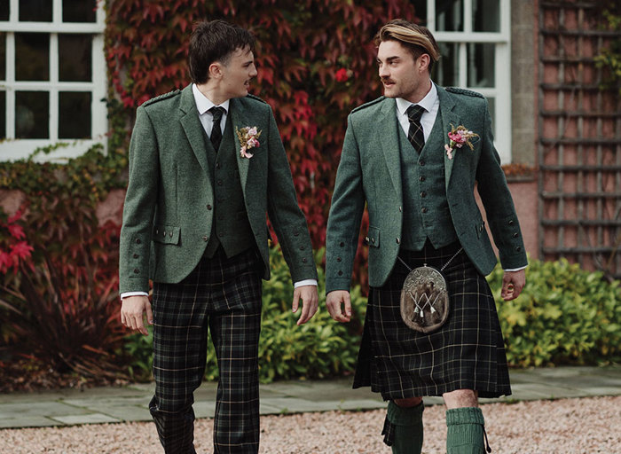 Two men in Highlandwear, both wearing green tones but one wearing trousers and one a kilt