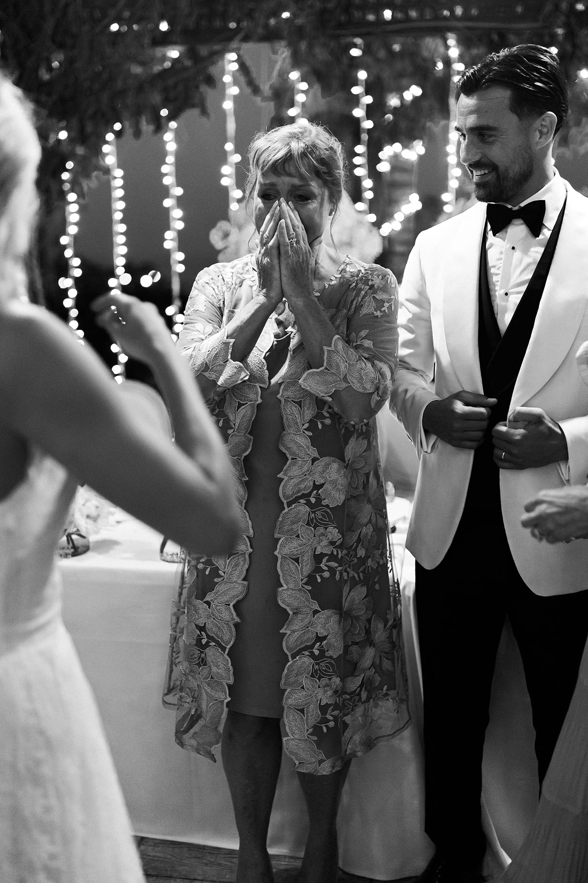 Groom’s mother wipes away tears during heartfelt evening celebration surrounded by fairy lights