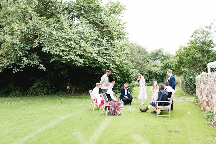 Guests sitting on chairs on the grass with groom