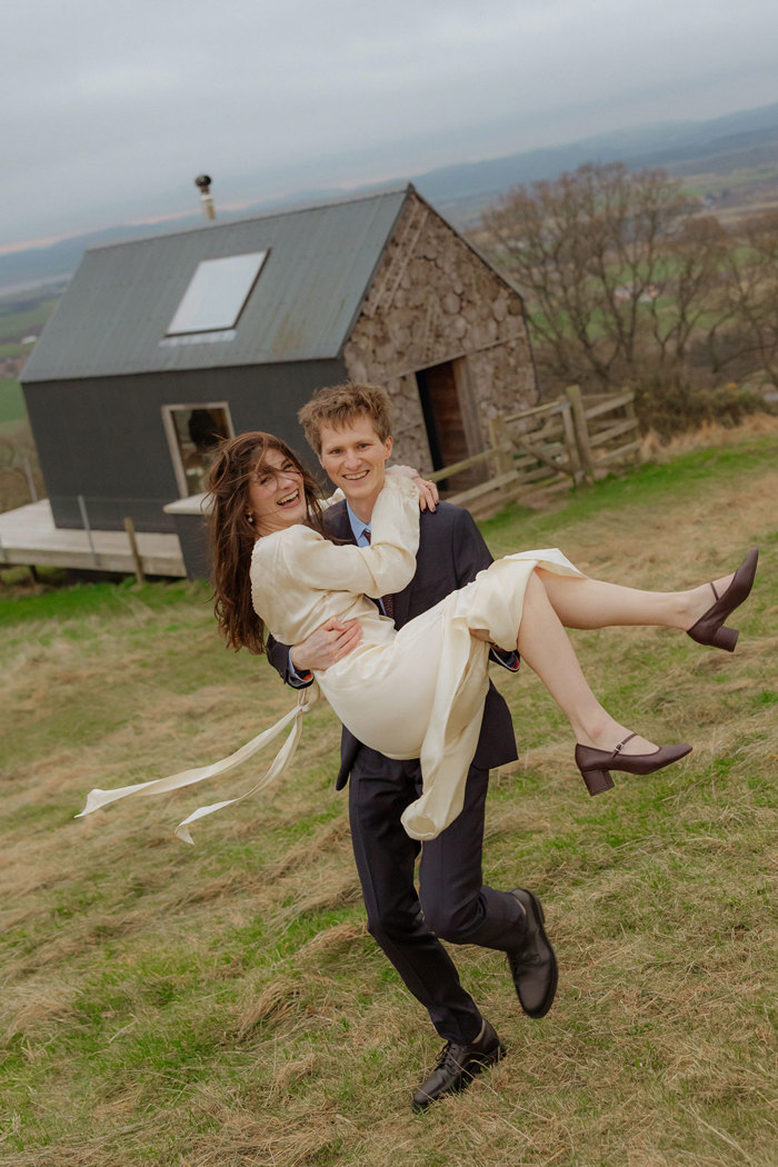 groom lifts up bride on windy day at guardswell farm