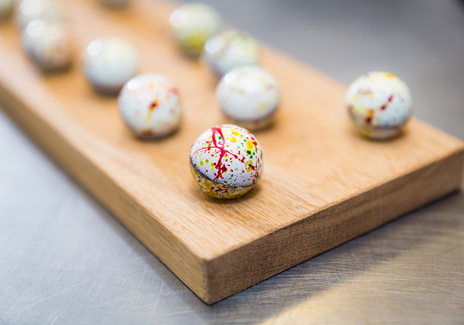 decorated white and coloured chocolates on wooden slab