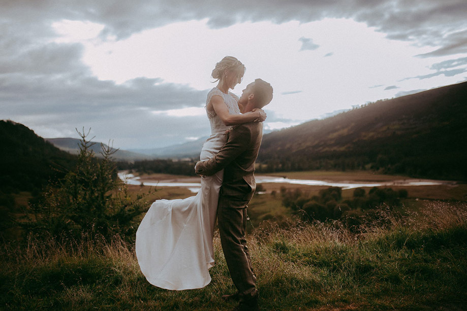 Groom picks up bride against scottish landscape at mar lodge