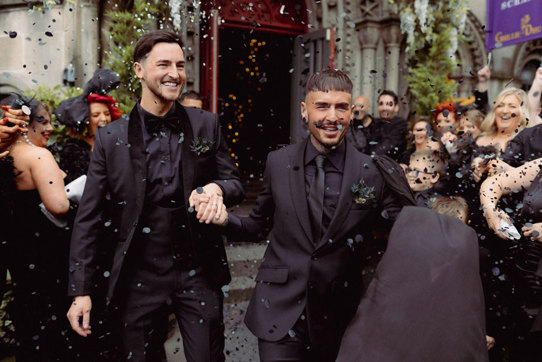 Two Men In Black Suits Holding Hands