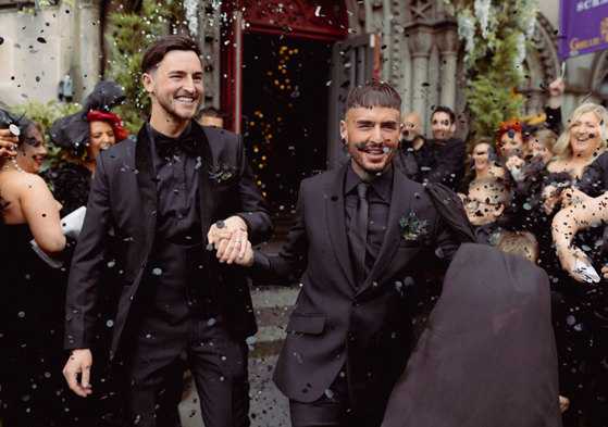 Two Men In Black Suits Holding Hands