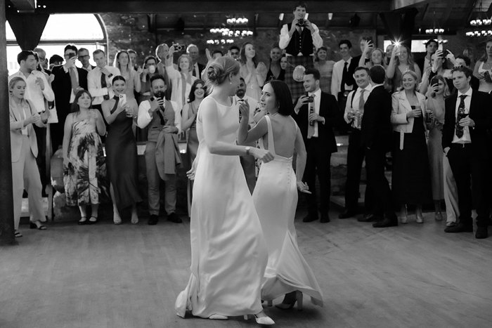two brides dancing while guests film during wedding at the Byre at Inchyra