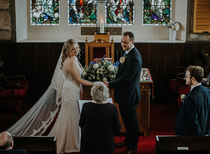 A bride and groom at the alter of a church during their ceremony