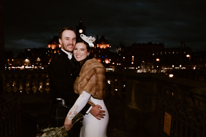 Photo of the bride and groom at night with Edinburgh skyline in background