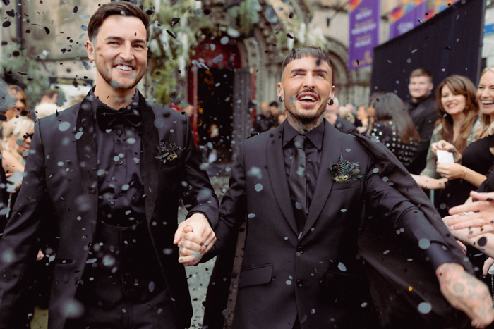 Two People Wearing Black Suits Holding Hands