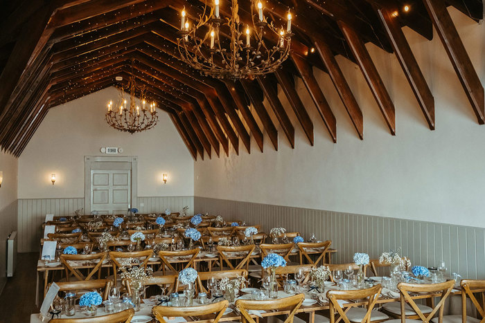 dinner set up with wooden chairs and blue decor at dougarie boathouse wedding