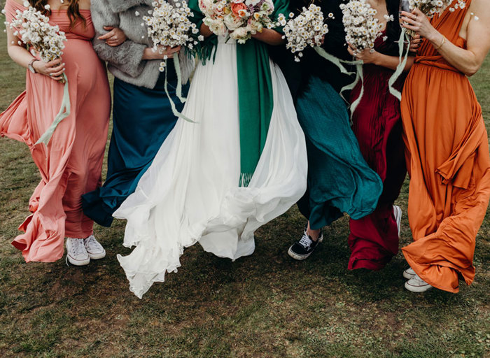bottom of colourful windswept skirts and bouquets standing on sandy-looking grass