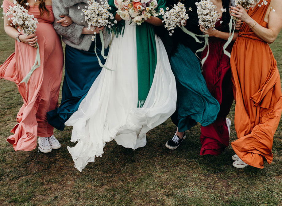 bottom of colourful windswept skirts and bouquets standing on sandy-looking grass
