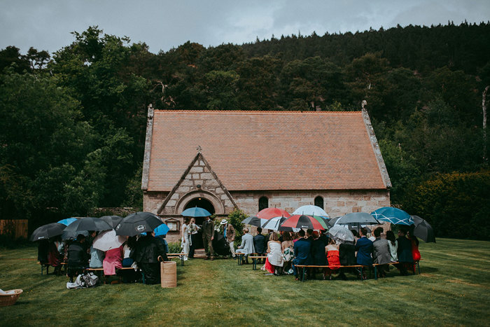 guests with umbrellas during outdoor ceremony at mar lodge