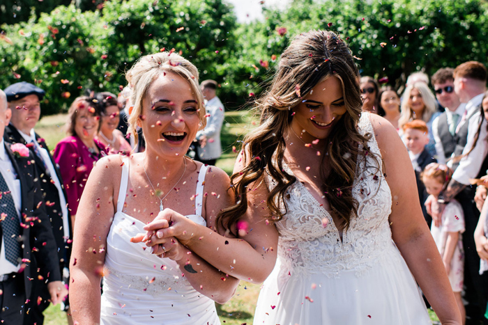 Confetti is thrown at the smiling brides