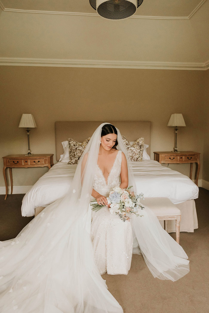 a bride sitting on an ottoman in a bedroom at Dunglass Estate
