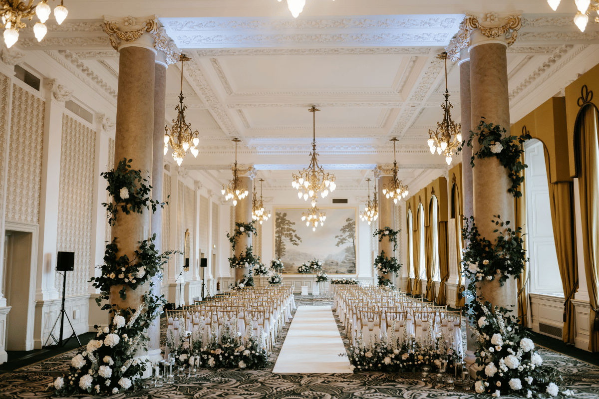 Sir Walter Scott Suite at The Balmoral Edinburgh set for a wedding ceremony with a white aisle, floral columns and rows of chairs