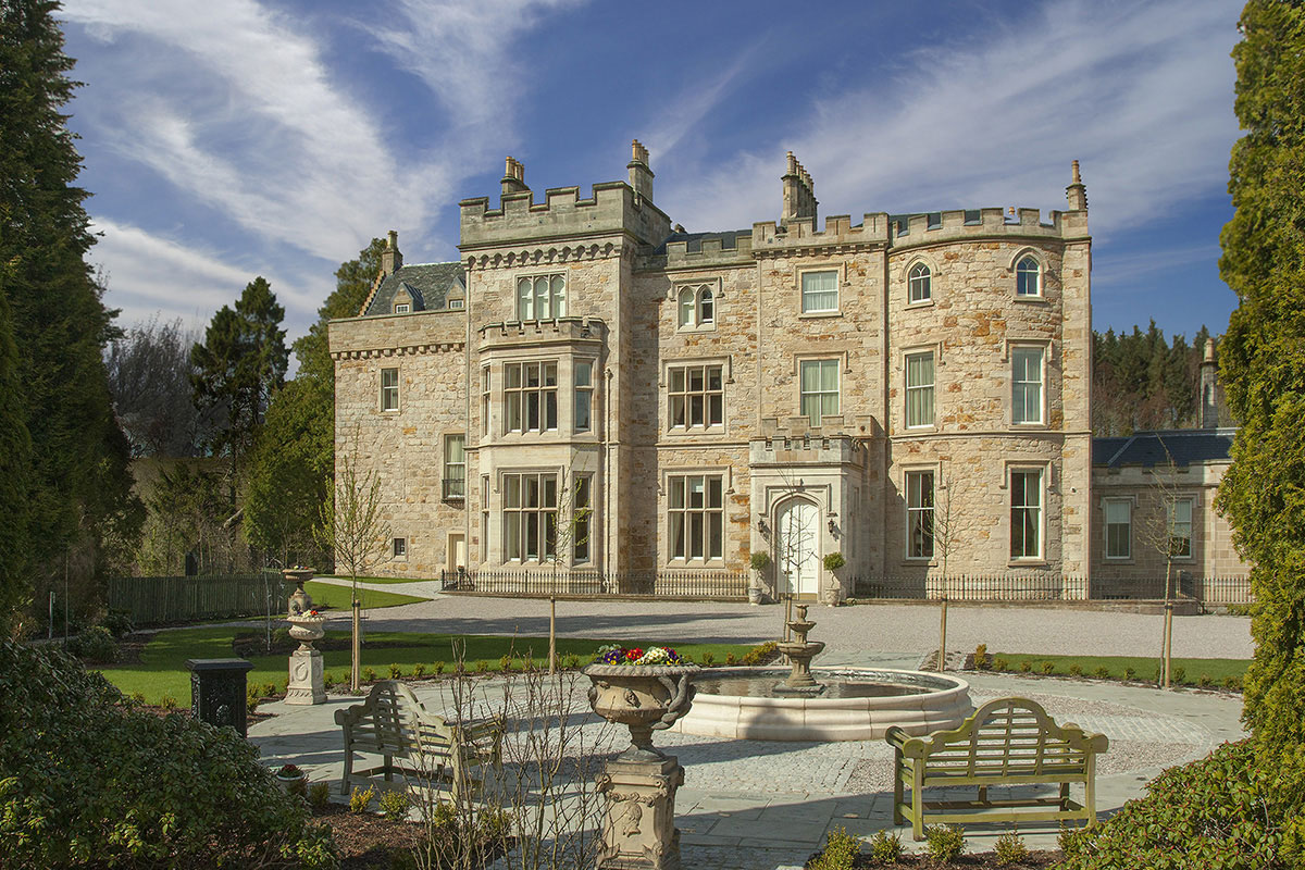 Exterior view of Crossbasket Castle in South Lanarkshire, highlighting the historic stone castle, courtyard fountain and landscaped gardens