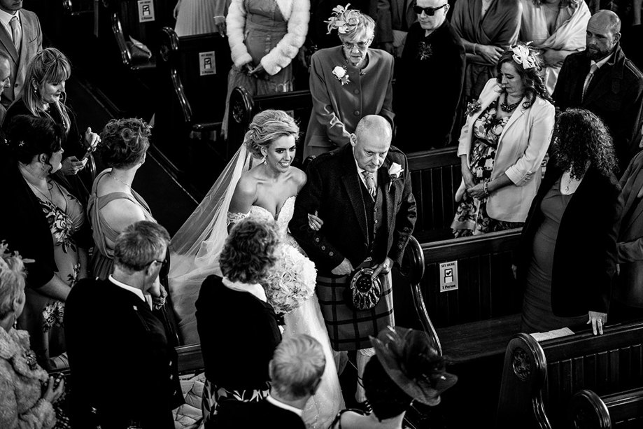 An Aerial Image Of A Bride Walking Down The Aisle Of St Peters & St Andrews Church In Thurso On The Arm Of A Man