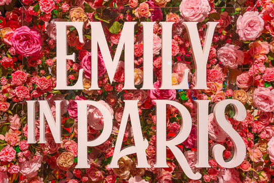 'Emily in Paris' signage in front of a wall of pink and red flowers