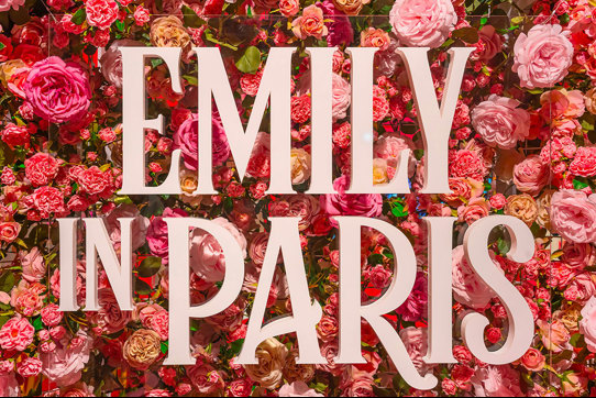 'Emily in Paris' signage in front of a wall of pink and red flowers