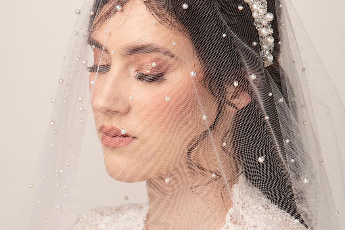 Bride wearing a pearl-detailed wedding veil with a coordinating pearl and crystal headpiece by Baba-C Designs.