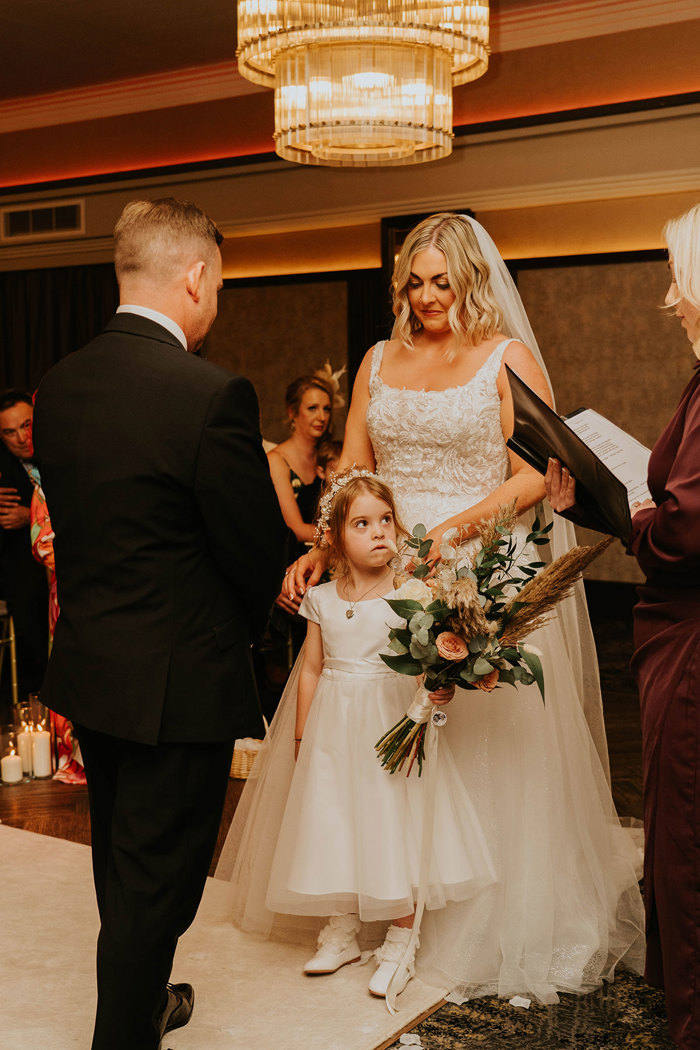 A bride and groom looking at a child.