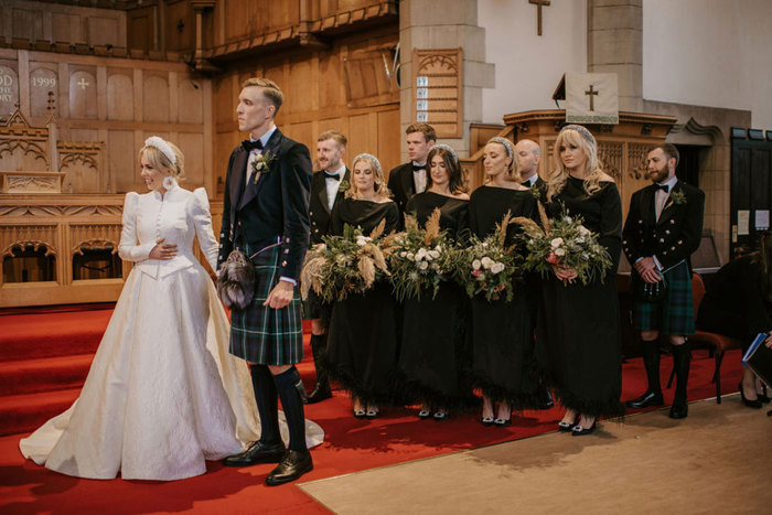 a bride and groom standing in a church with their wedding party behind them