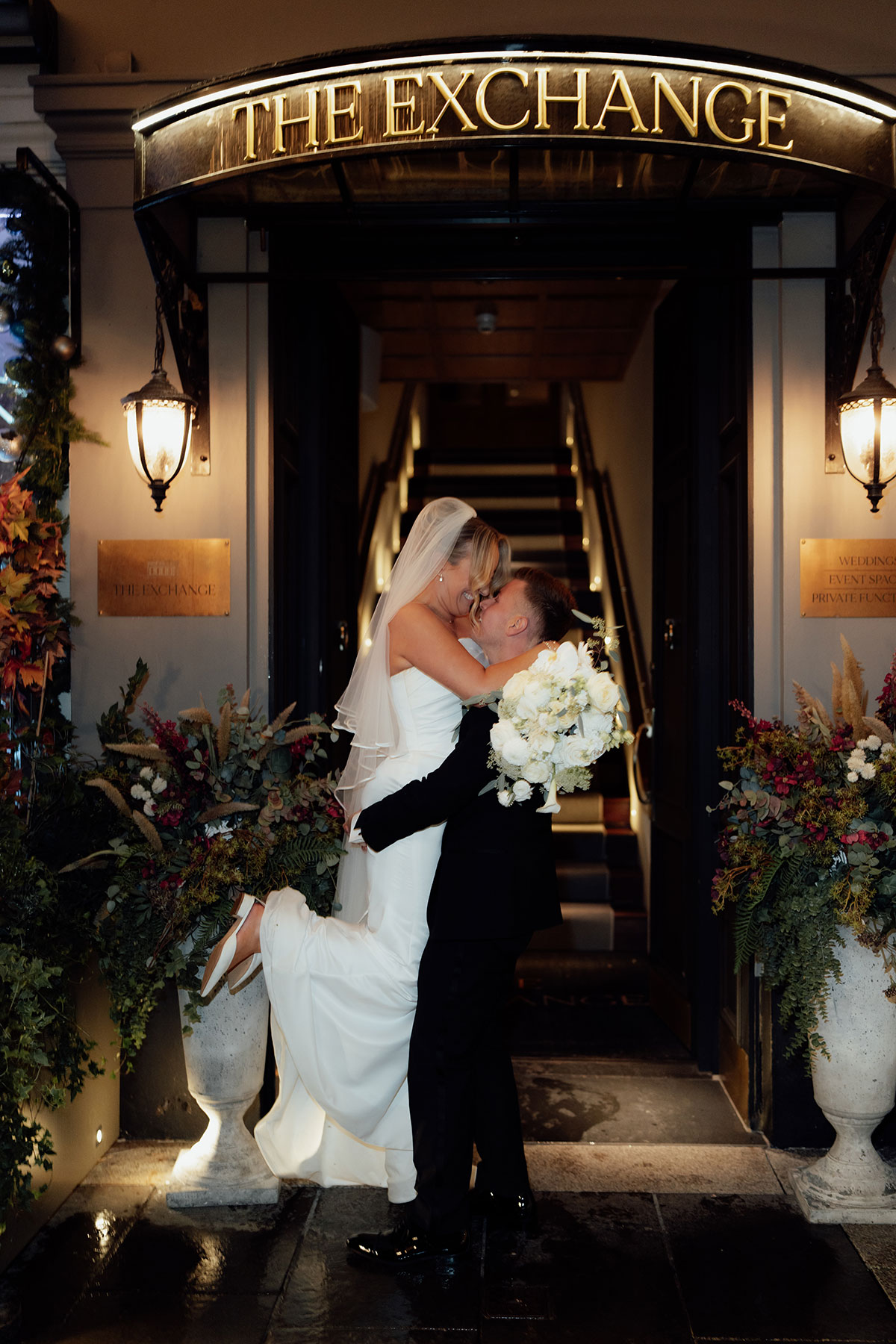 Bride and groom kissing outside The Exchange wedding venue in Glasgow entrance at night