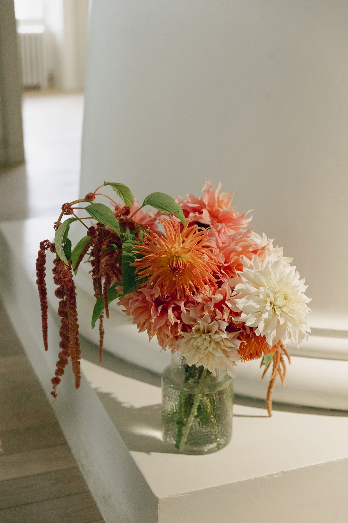 Autumn dahlias in peach and ivory arranged in a glass vase during wedding morning preparations at The Hoxton Edinburgh.