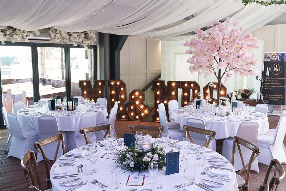 Wedding reception styling at The Venue at Duntarvie Castle with round tables, illuminated initials and blossom tree décor