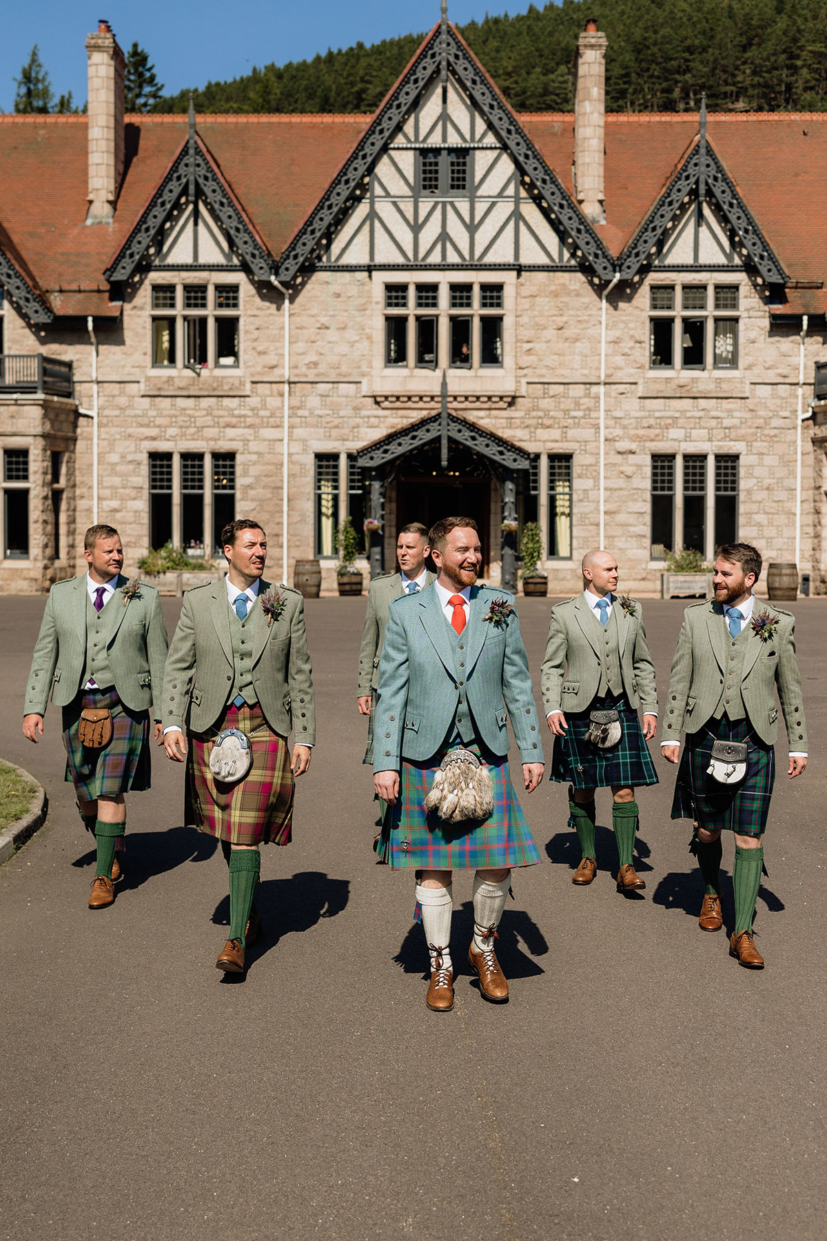 Groom and groomsmen in traditional Scottish kilts outside Mar Lodge Estate before the wedding ceremony