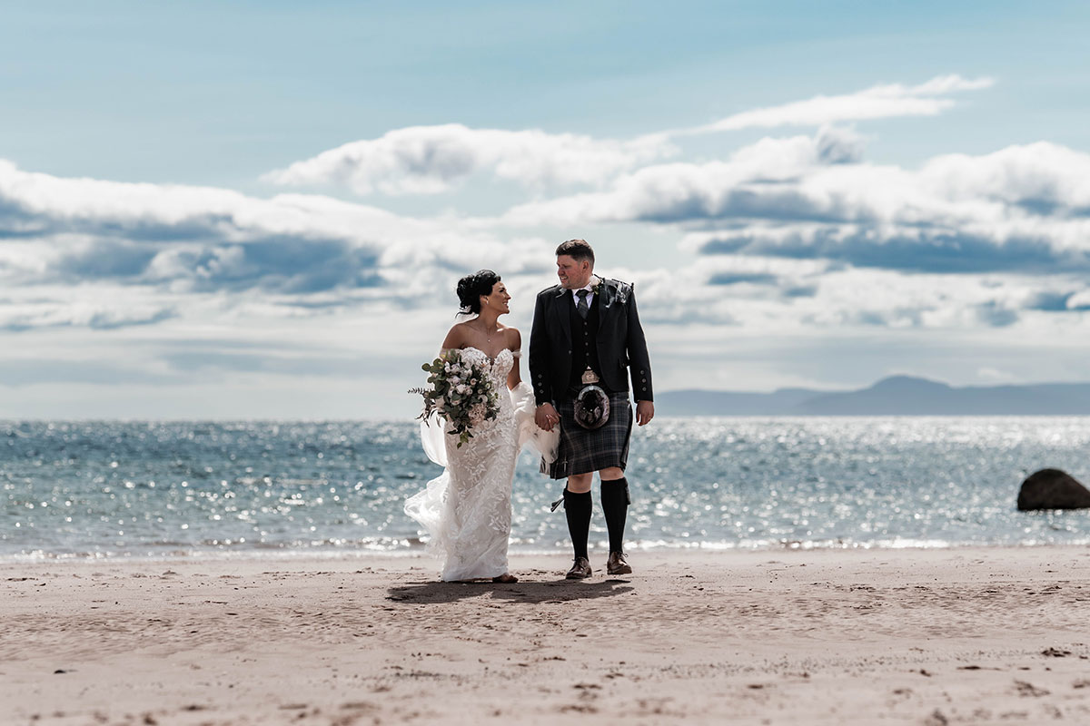 Bride and groom walking on the beach beside The Waterside Hotel, Ayrshire wedding venue