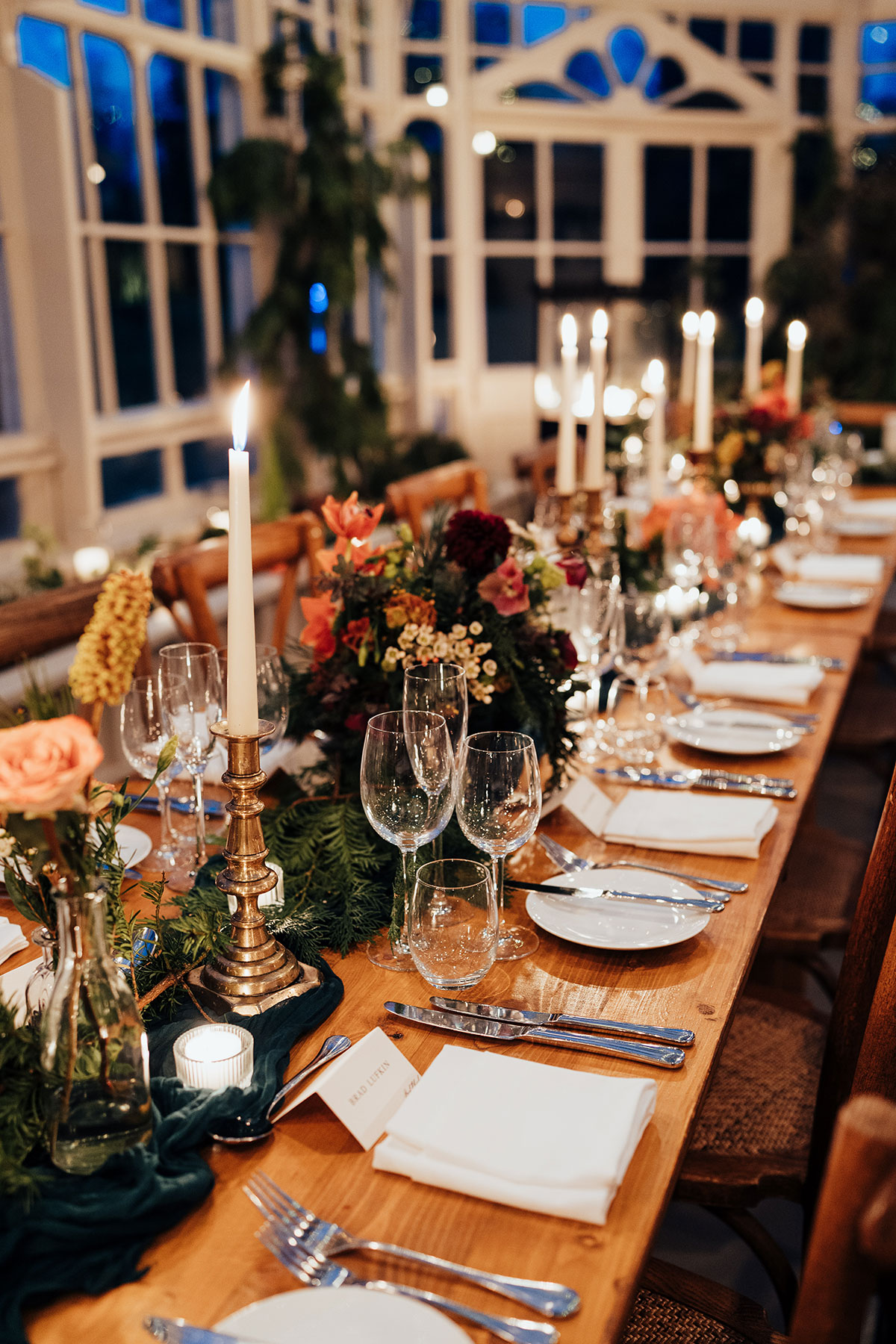 Long reception table styled with candles, greenery and colourful floral arrangements
