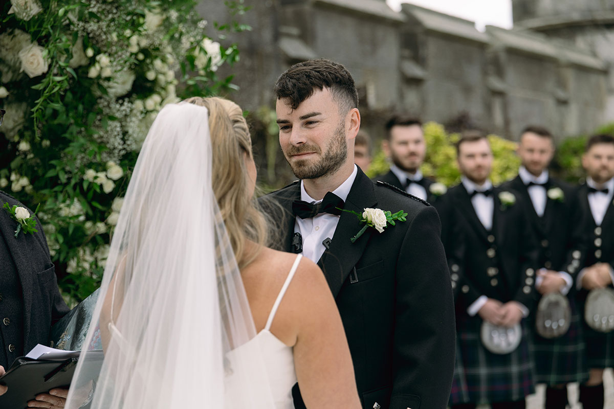 Bride and groom exchange vows at Dundas Castle courtyard surrounded by bridesmaids and groomsmen.
