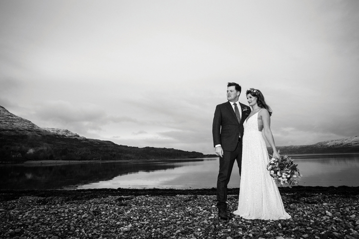 Black and white image of the bride and groom at the edge of a loch