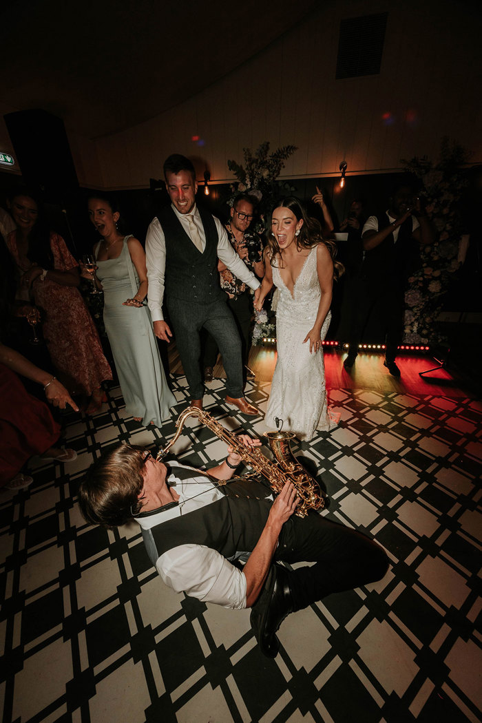 a saxophonist performing on his knees on the floor during a reception at Dunglass Estate