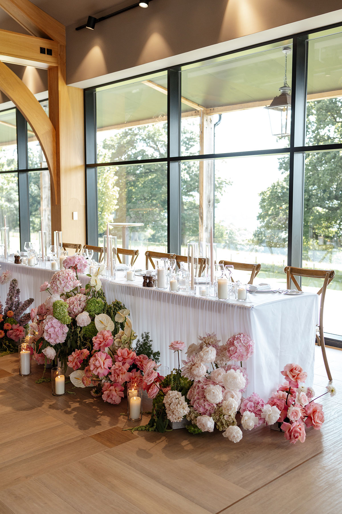 Elegant top table at Boturich Castle decorated with abundant pink floral arrangements, candles and modern wedding styling.